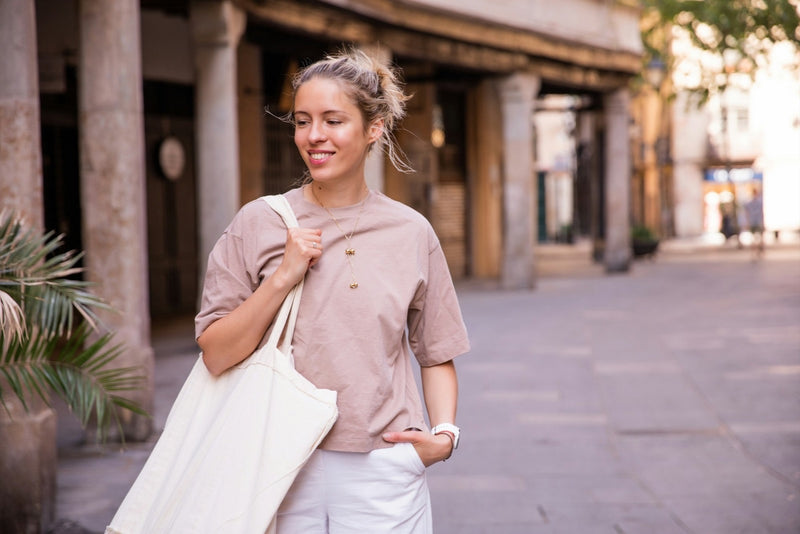 Femme souriante portant un cabas clair en pleine rue