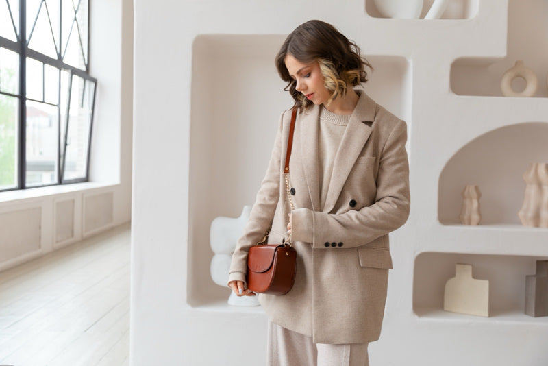 Femme en manteau clair, sac porté à l'épaule