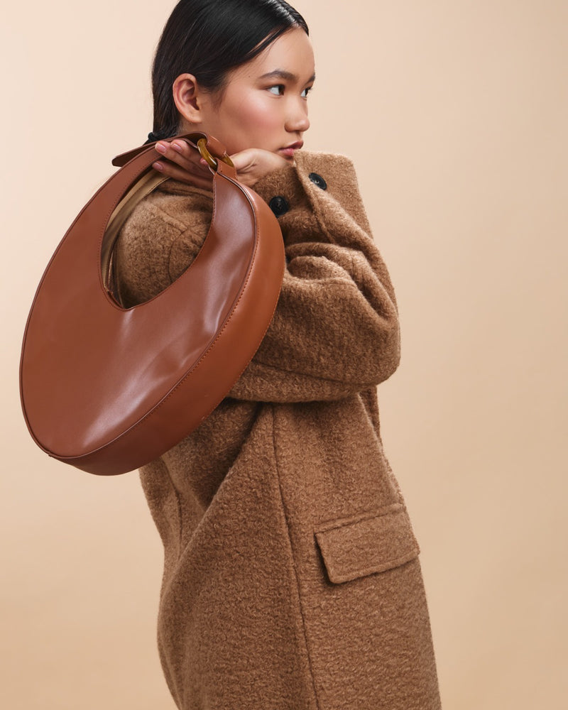 Femme portant un sac en cuir clair, en extérieur